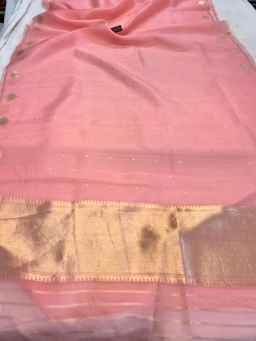 Pure Banarasi handloom Kora silk saree by Aura Benaras with small Kadhwa butis, a designer Banarasi border with Kadhwa butas, and silk blouse featuring golden zari stripes—ideal for weddings and festive wear.