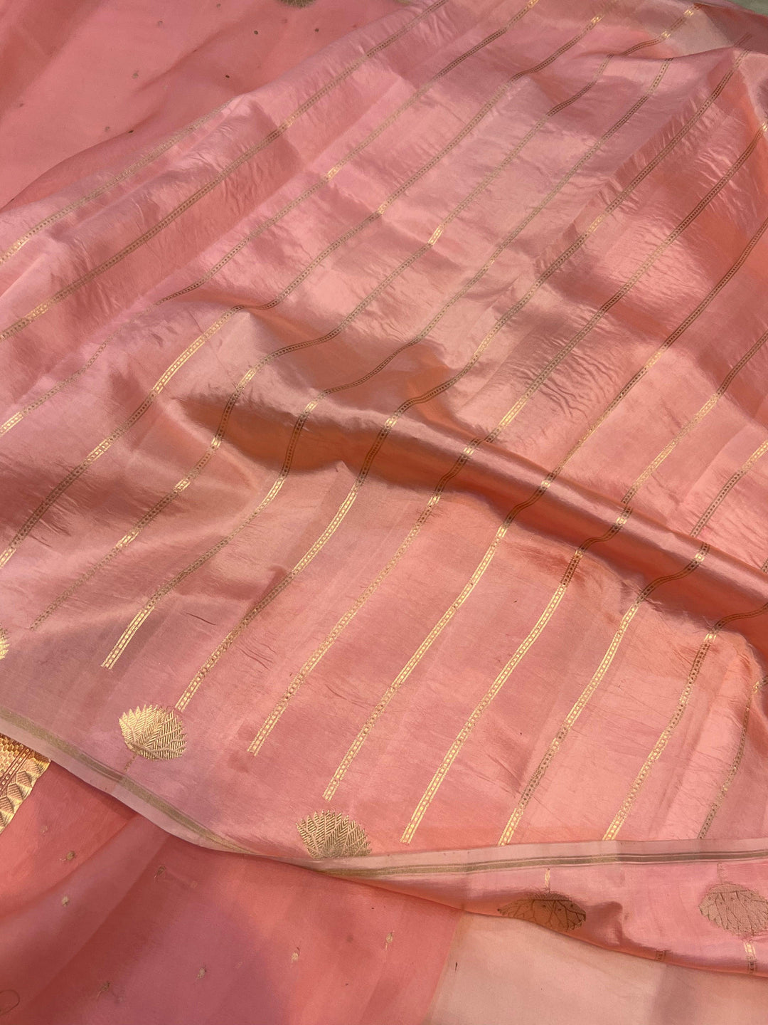 Pure Banarasi handloom Kora silk saree by Aura Benaras with small Kadhwa butis, a designer Banarasi border with Kadhwa butas, and silk blouse featuring golden zari stripes—ideal for weddings and festive wear.