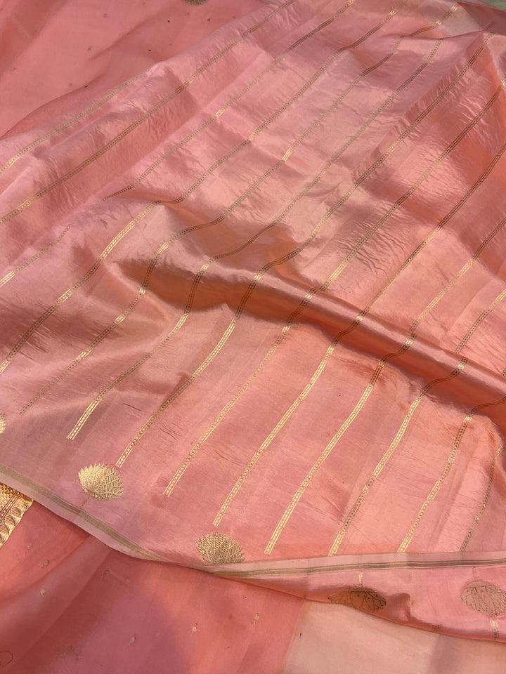 Pure Banarasi handloom Kora silk saree by Aura Benaras with small Kadhwa butis, a designer Banarasi border with Kadhwa butas, and silk blouse featuring golden zari stripes—ideal for weddings and festive wear.