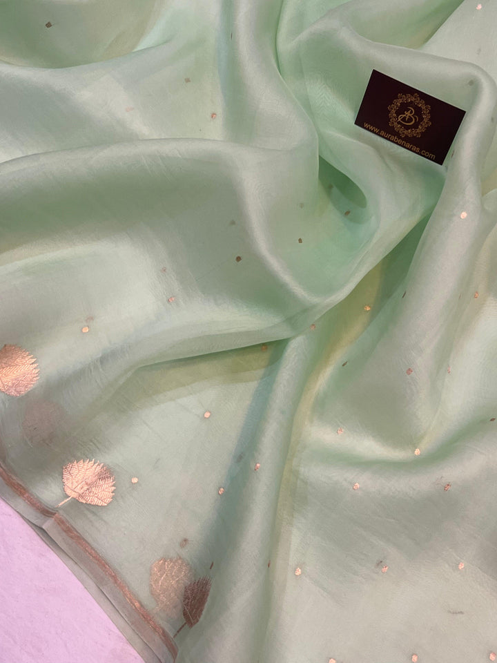 Pure Banarasi handloom Kora silk saree by Aura Benaras with small Kadhwa butis, a designer Banarasi border with Kadhwa butas, and silk blouse featuring golden zari stripes—ideal for weddings and festive wear.