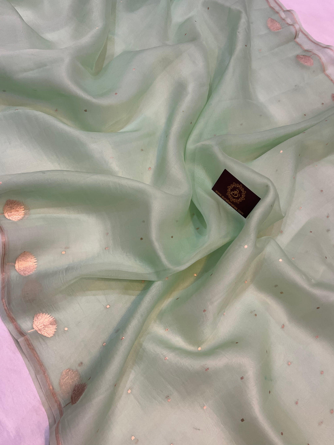 Pure Banarasi handloom Kora silk saree by Aura Benaras with small Kadhwa butis, a designer Banarasi border with Kadhwa butas, and silk blouse featuring golden zari stripes—ideal for weddings and festive wear.