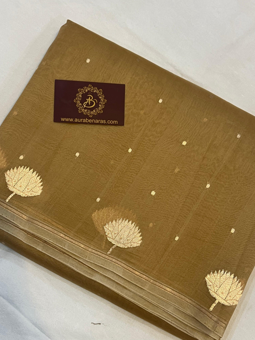 Pure Banarasi handloom Kora silk saree by Aura Benaras with small Kadhwa butis, a designer Banarasi border with Kadhwa butas, and silk blouse featuring golden zari stripes—ideal for weddings and festive wear.