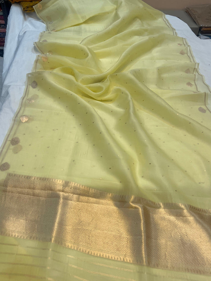 Pure Banarasi handloom Kora silk saree by Aura Benaras with small Kadhwa butis, a designer Banarasi border with Kadhwa butas, and silk blouse featuring golden zari stripes—ideal for weddings and festive