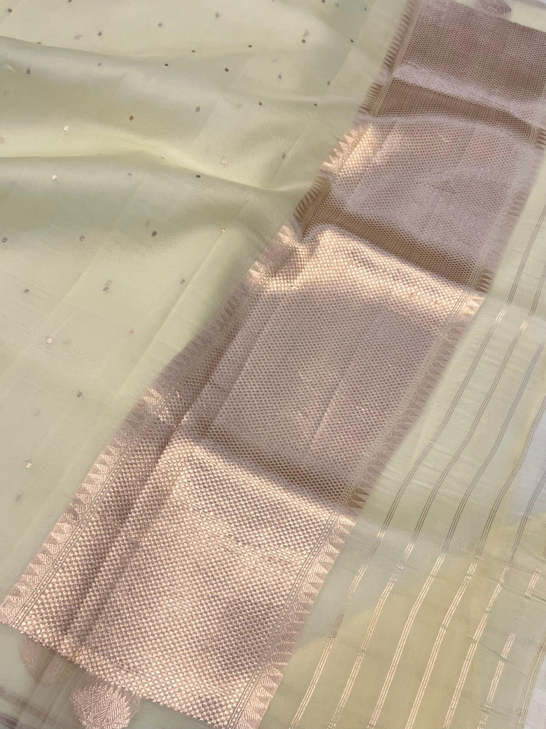 Pure Banarasi handloom Kora silk saree by Aura Benaras with small Kadhwa butis, a designer Banarasi border with Kadhwa butas, and silk blouse featuring golden zari stripes—ideal for weddings and festive