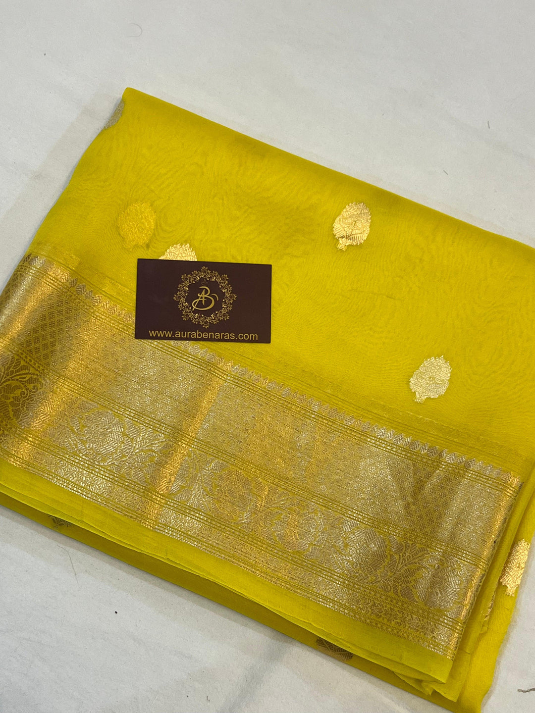 Pure Banarasi handloom Kora silk saree by Aura Benaras, featuring intricate Kadhwa butas and a beautiful traditional Banarasi border—ideal for weddings, festive wear, and special occasions.