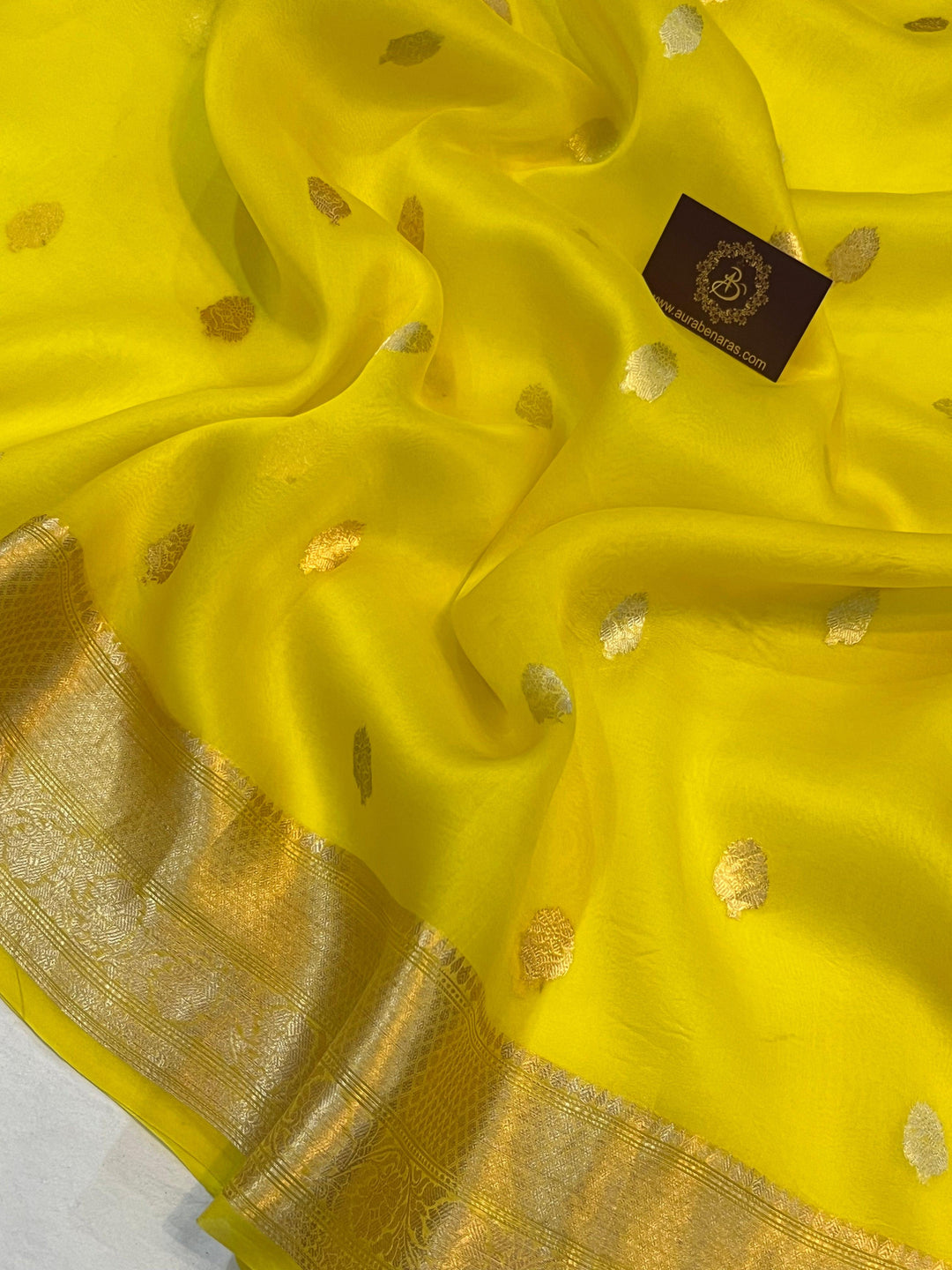 Pure Banarasi handloom Kora silk saree by Aura Benaras, featuring intricate Kadhwa butas and a beautiful traditional Banarasi border—ideal for weddings, festive wear, and special occasions.