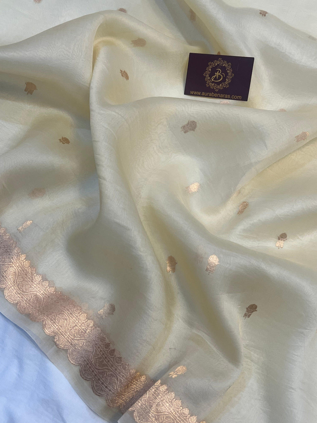 Detailed view of small golden zari butis on sheer Kora silk fabric, showcasing traditional Kadhwa weaving